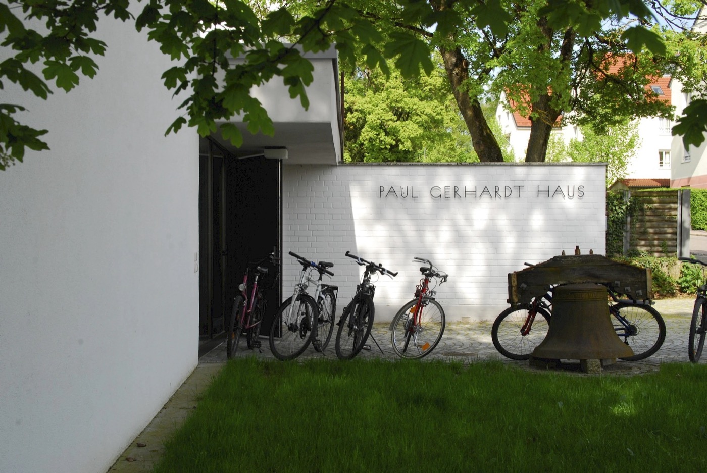 Paul-Gerhardt-Haus Freising — Schriftzug an der Außenwand mit historischer Glocke